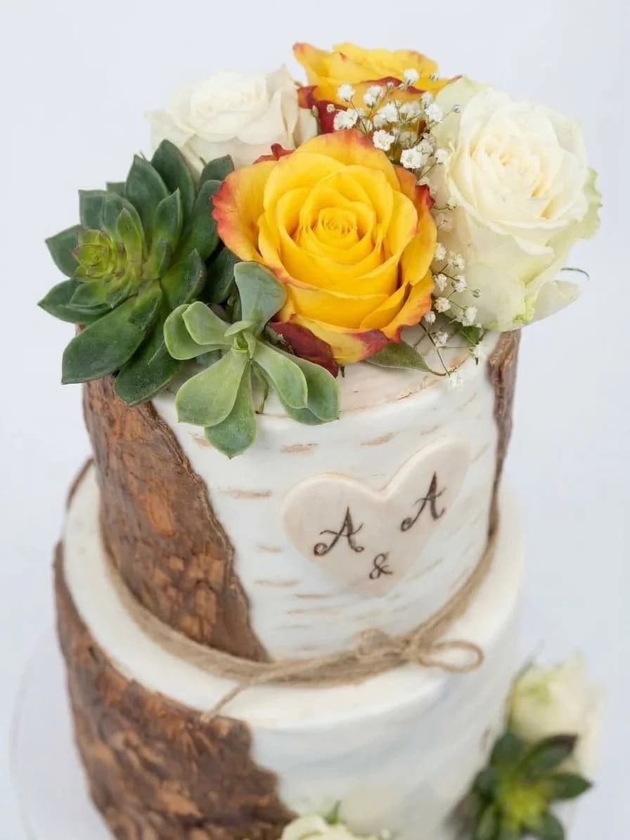 Vue rapprochée d'un gâteau façon écorce surmonté de roses jaunes et de succulentes